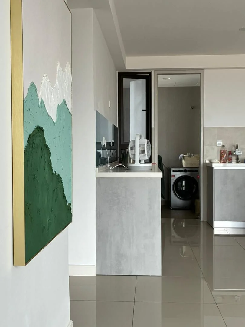 Room features: grey painted walls, glossy tile flooring, kitchen countertop with grey finish, built-in cabinetry, recessed lighting, kettle, washing machine, framed artwork on wall; style: modern.